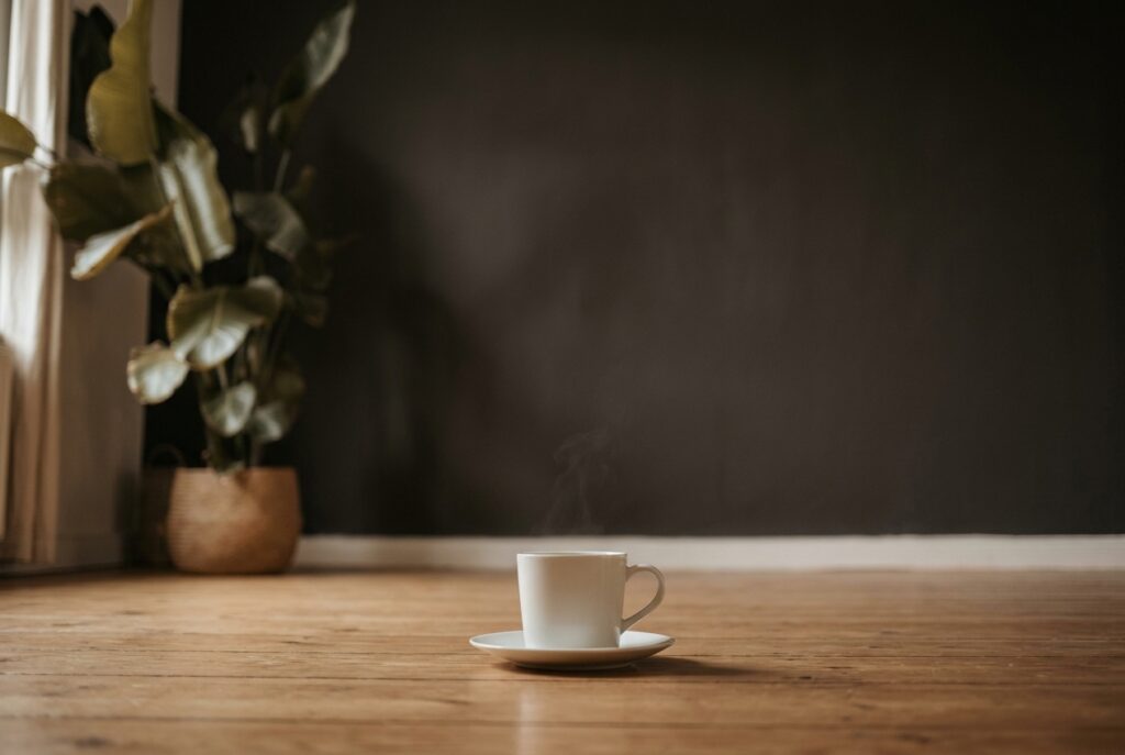 Dampfende Tasse auf Holztisch — ruhiger Moment als Sinnbild für Stress-Regulation und Cortisol-Senkung. Wellness Atelier Hermle, Groß Molzahn nahe Ratzeburg und Lübeck.